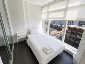 a white bed in a room with a large window at Moden & Cozy Downtown Condo in Vancouver in Vancouver