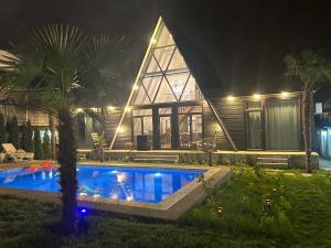 a house with a swimming pool in front of it at night at Qafqaz Mountside Chalet in Gabala