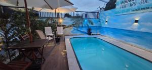 a swimming pool with a table and an umbrella at Pousada Primeiro Sol in João Pessoa