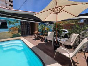 a patio with a swimming pool and an umbrella at Pousada Primeiro Sol in João Pessoa