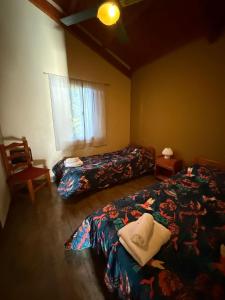 a bedroom with two beds and a chair and a window at Cabañas Ojo de Agua in Sierra de la Ventana +33 photos