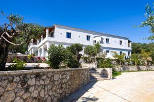 ein großes weißes Haus mit einer Steinmauer in der Unterkunft Crystal Blue Hotel, Barbati, Corfu in Barbati