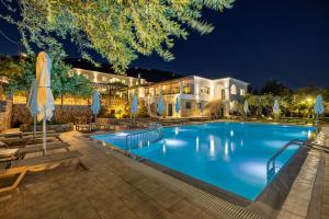 ein Schwimmbad mit Liegestühlen und Sonnenschirmen vor einem Gebäude in der Unterkunft Crystal Blue Hotel, Barbati, Corfu in Barbati