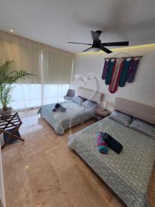 a living room with two beds and a ceiling fan at Private Suite, Walk to the Beach, Oceanview Rooftop Pool, WiFi StarLink in Puerto Morelos