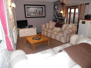 a living room with couches and a christmas tree at Primrose Cottage in North Petherwin