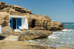 two chairs sitting in front of a blue door on the beach at Thavma Beach House in Mytakas