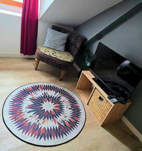 a living room with a rug and a chair and a television at Cocon industriel pour Nuits étoilées in Bourges