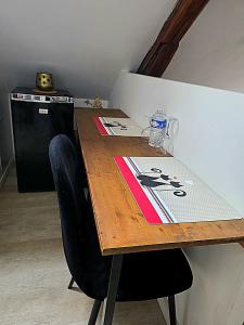 a wooden table with two chairs and a refrigerator at Cocon industriel pour Nuits étoilées in Bourges
