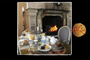 a table with food and a fireplace in a room at Manoir de Livet in Saint-Germain-de-Livet