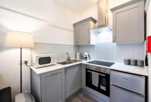 a white kitchen with a sink and a microwave at Coastal Nest - Cosy flat in Irvine town centre - 5 minute drive from beach in Irvine +5 photos