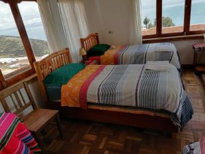 two beds in a room with a window at Hostal Inti Wayra in Comunidad Yumani
