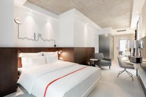 ein Schlafzimmer mit einem großen weißen Bett und einem Schreibtisch in der Unterkunft Ruby Ella Hotel Cologne by IHG in Köln