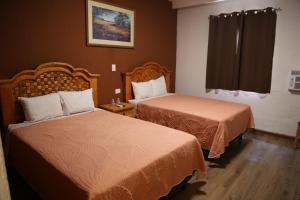 ein Hotelzimmer mit zwei Betten und einem Fenster in der Unterkunft Hotel Colonial in Monterrey