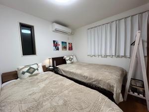 a bedroom with two beds and a ladder and a window at 白樺ハウス女性&家族専用 送迎あり小型犬可 in Chigasaki