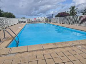 a large blue swimming pool with a white fence at Residence le bounty in Sainte-Luce