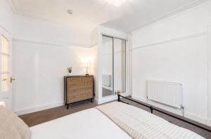 a bedroom with a bed and a dresser and a window at Coastal Nest - Cosy flat in Irvine town centre - 5 minute drive from beach in Irvine