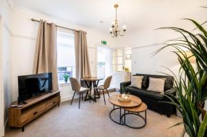 a living room with a couch and a tv and a table at Coastal Nest - Cosy flat in Irvine town centre - 5 minute drive from beach in Irvine