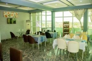 a dining room with tables and chairs and windows at NI-FUR Hotel Cotonou in Cotonou