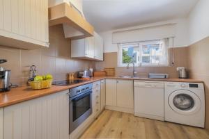 a kitchen with white cabinets and a washer and dryer at Vila Vista Luz in Lagos +59 photos