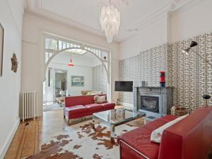 a living room with a red couch and a fireplace at La Maison Bleue petite in Ronse