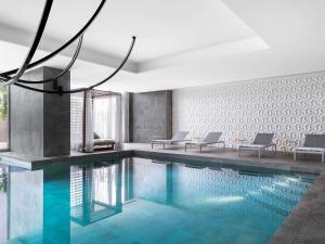 a swimming pool with two chairs and a chandelier at Novotel Convention And Spa in Antananarivo