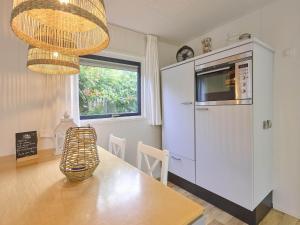 a kitchen with a table and a refrigerator and a window at Chalet Sea Birds in Goedereede