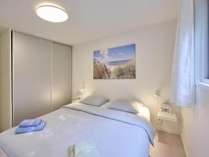 a white bedroom with a bed and a picture on the wall at Chalet Sea Birds in Goedereede