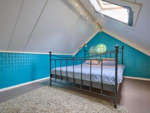 a bedroom with blue walls and a bed in a attic at Twente Village in Haaksbergen