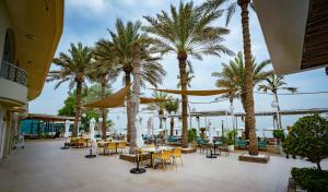 a patio with tables and chairs and palm trees at Occidental Sharjah Grand in Sharjah