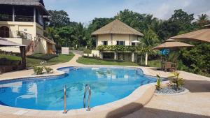 a large swimming pool in front of a house at The Halfway Cafe-Dauin, Glamp2 - Grasshopper in Dauin