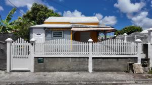 a white picket fence with a house behind it at Ti kaz a fredo in Port-Louis