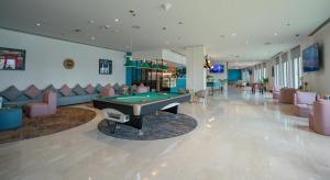 a billiard room with a pool table and couches at Occidental Sharjah Grand in Sharjah