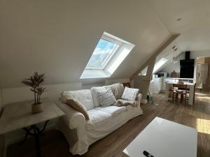 a living room with a white couch and a window at Bel appartement sous combles in Argelès-Gazost