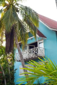 a blue building with a balcony and palm trees at Hotel Isla Azul - Islas del Rosario in Isla Grande