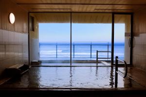a bathroom with a tub with a view of the ocean at Wakamatsu Hot Spring Resort in Hakodate