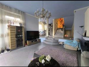 a living room with a chandelier and a couch and a television at Panorama Hills Villa in Budapest