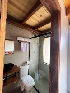a bathroom with a toilet and a glass shower at Chalé Pontal da Juacema in Ilha Cachoeira