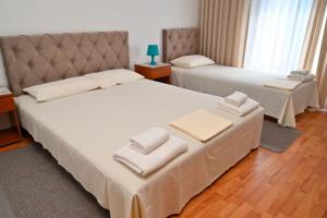 two beds in a hotel room with towels on them at Adriatic Garden Rooms in Bregvija