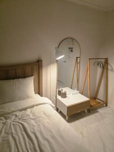 a bedroom with a bed and a mirror and a table at Stay GaeBong in Seoul