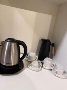 a tea kettle and four cups and saucers on a counter at Refugio Centrico in Ciudad del Este