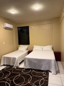 a room with two beds and a tv on the wall at Refugio Centrico in Ciudad del Este +9 photos