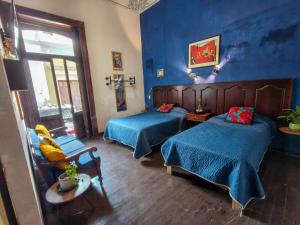 a blue room with two beds and a chair at Villa Catrina in Morelia
