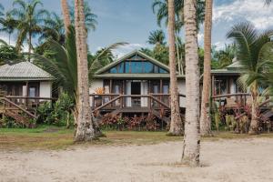 a house with palm trees in front of it at Sinalei Reef Resort & Spa in Maninoa