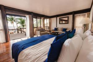 a bedroom with a large bed with blue and white pillows at Sinalei Reef Resort & Spa in Maninoa
