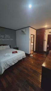 a bedroom with a white bed and a wooden floor at DaViKa Vientiane Hotel in Vientiane