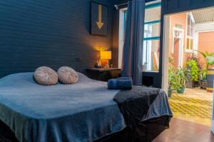 a blue bedroom with a bed with blue sheets and pillows at The Nomad Hostel - SJO Airport San Jose 5 min - Private, WiFi & Coffee in Alajuela