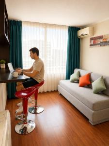 a man sitting at a table with a laptop in a living room at Departamentos Amoblados Torre Tagle in Santiago