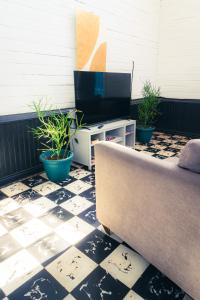a couch sitting on a tiled floor with potted plants at The Nomad Hostel - SJO Airport San Jose 5 min - Private, WiFi & Coffee in Alajuela