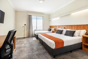 a hotel room with two beds and a television at Metro Hotel Perth City in Perth