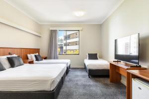a hotel room with two beds and a flat screen tv at Metro Hotel Perth City in Perth +47 photos